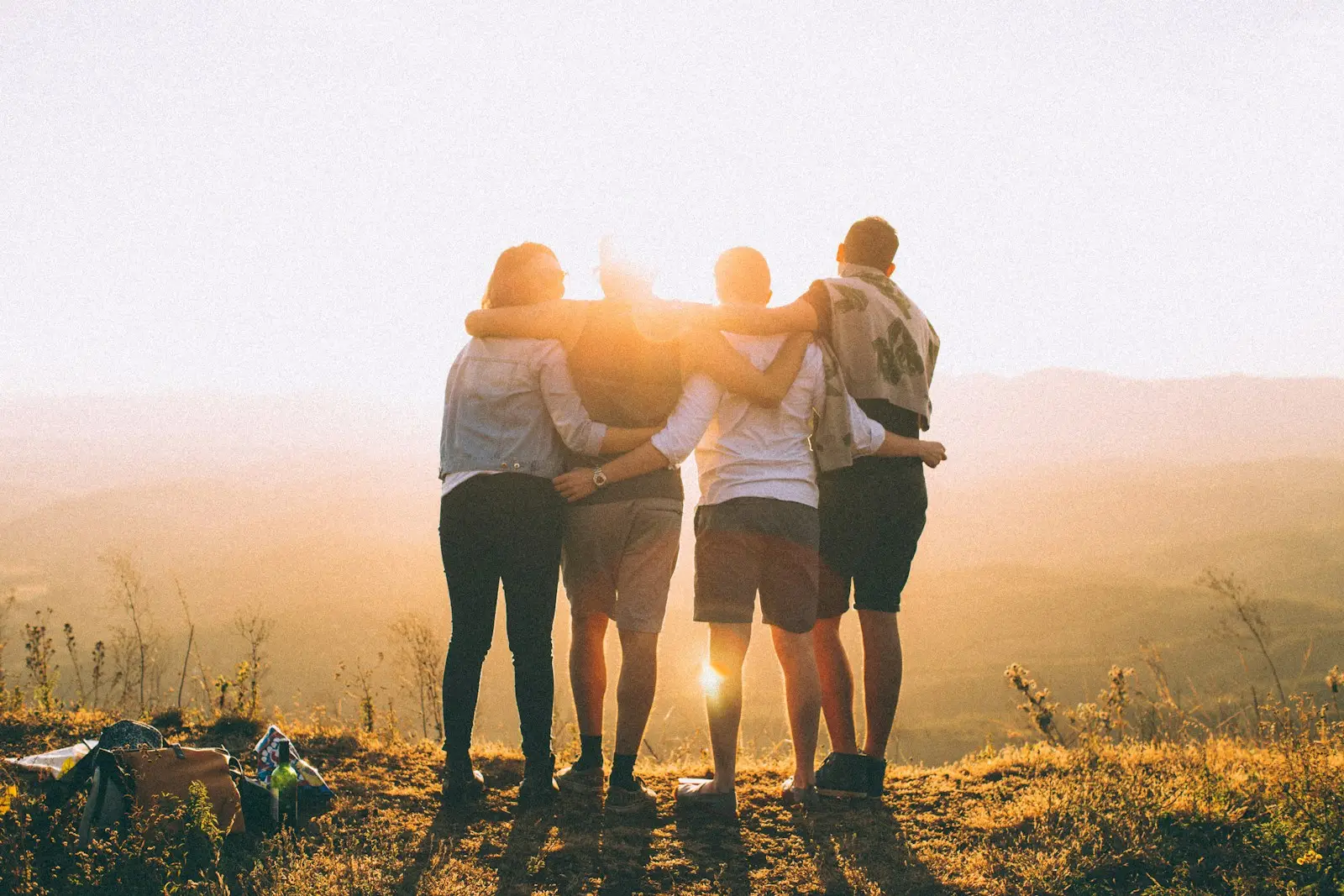 Quatres personnes ne serrent dans le bras devant un coucher de soleil