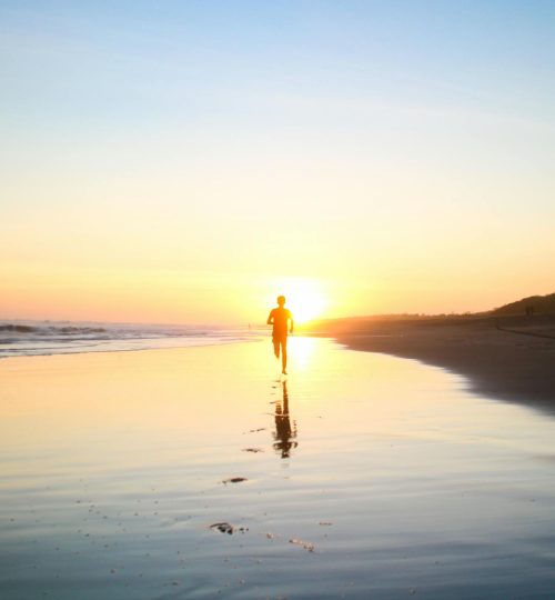 Silhouette of Boy Running in Body of Water during Sunset