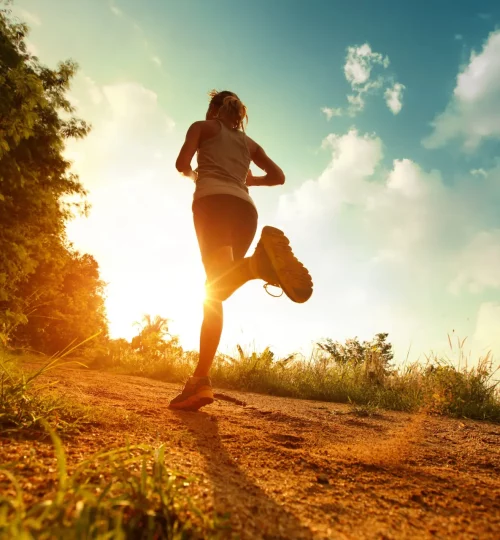 Sportif qui court sur du sable à contre jour