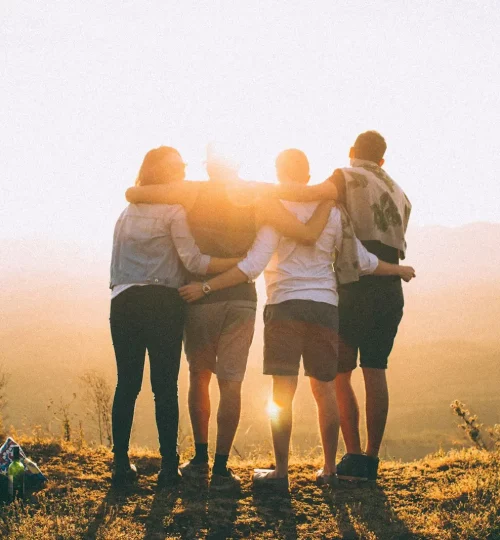 Quatres personnes ne serrent dans le bras devant un coucher de soleil