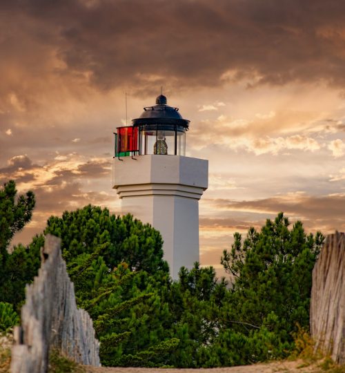 a white lighthouse with a red light on top of it
